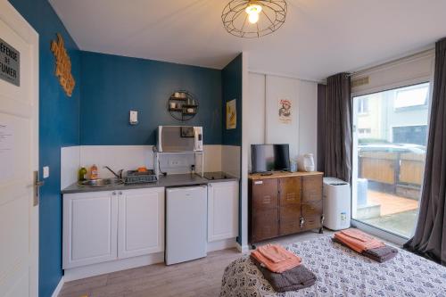 une cuisine avec des armoires blanches et un mur bleu dans l'établissement Le Studio de M.Hulot - Climatisé proche plage, à Saint-Nazaire