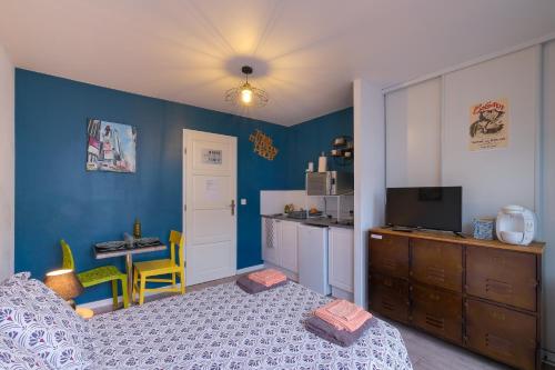 Cet appartement comprend une chambre avec des murs bleus, un lit et une cuisine. dans l'établissement Le Studio de M.Hulot - Climatisé proche plage, à Saint-Nazaire
