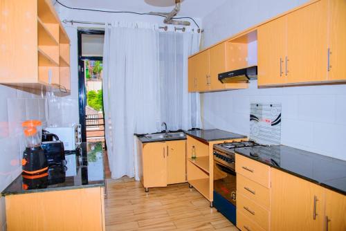 a kitchen with wooden cabinets and black counter tops at Diplomat Apartments Rugando in Kigali