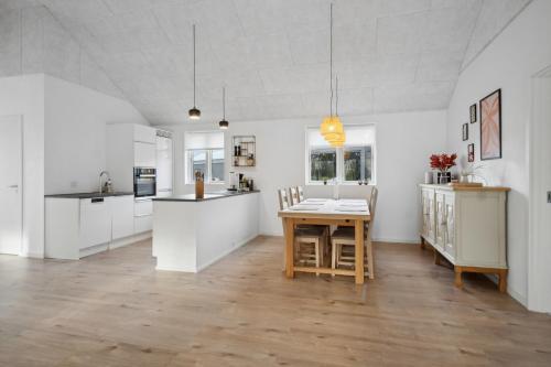 a kitchen with white cabinets and a wooden table at Sommerhus i Arrild Ferieby nær Vesterhavet in Arrild