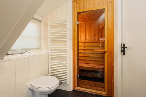a bathroom with a toilet and a wooden door at Buitengoed het Lageveld 64 in Hoge-Hexel