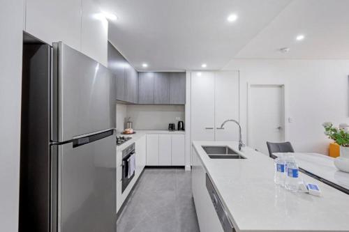 a kitchen with white cabinets and a refrigerator at Luxury Loft 3 Bed, 2 Bath, Sleeps 6, Pool, BBQ, No parties in Sydney