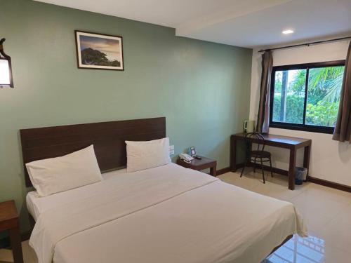 a bedroom with a bed and a desk and a window at Chalicha Resort in Chumphon