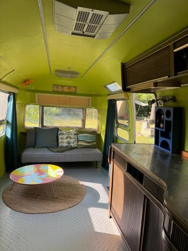 une caravane verte avec un canapé et une table. dans l'établissement Camping De Thoissey ***, à Thoissey