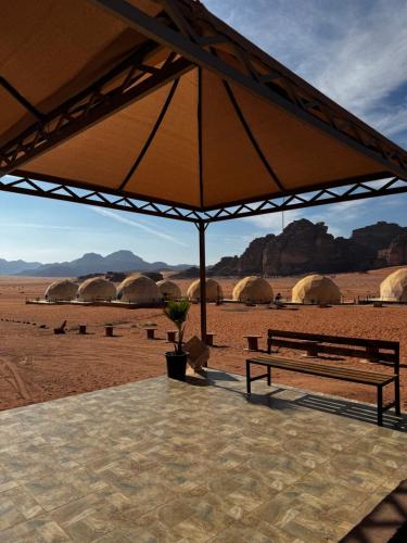 a bench under a large umbrella in the desert at Rum Angel Camp in Wadi Rum