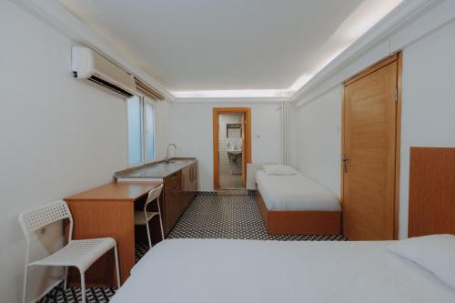 a room with two beds and a desk and a sink at Deniz Pansiyon in İzmir