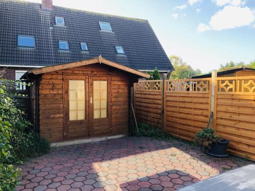 une cabane en bois avec une clôture devant elle dans l'établissement Ferienhaus Norddeich 27, à Norden
