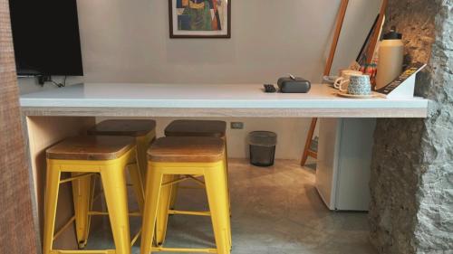 a kitchen with two yellow stools and a counter at Chill Roof Hotel in Taipei