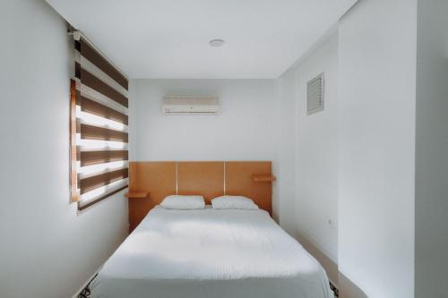 Un dormitorio pequeño con una cama blanca con una ventana. en Deniz Pansiyon, en Izmir