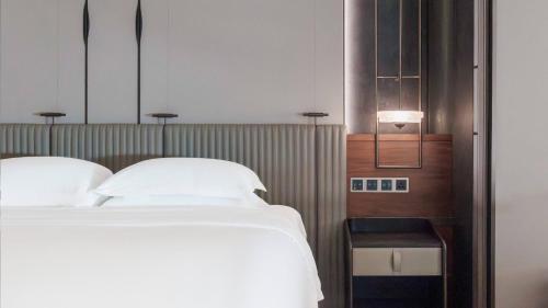 a bedroom with a bed with white pillows at InterContinental Haikou Seaview by IHG in Haikou