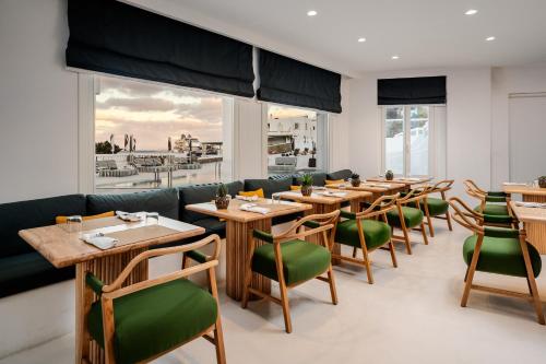a restaurant with wooden tables and green chairs at Croco Mykonos in Tourlos
