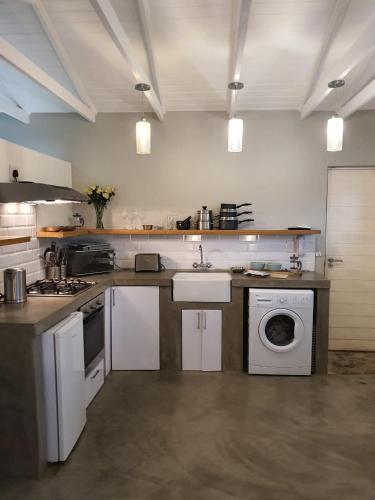 a kitchen with a sink and a washing machine at Blouberg Rise Cottage in Cape Town