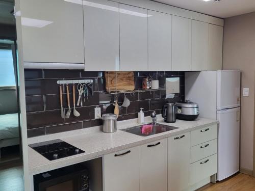 a kitchen with white cabinets and a sink at Greece - Foreigners only in Gyeongju
