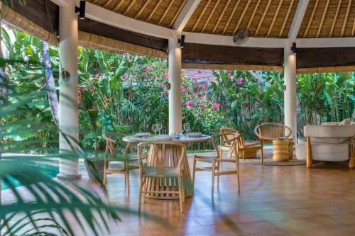 een patio met tafels, stoelen en planten bij Flor Villa by Betterplace in Dalung