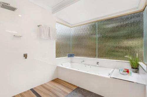 a white bathroom with a tub and a window at Seven Mile Beach Holiday Park in Gerroa