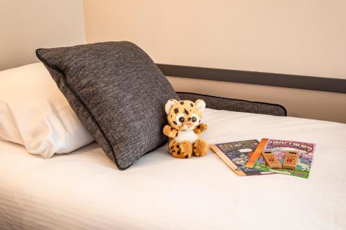 a teddy bear sitting on a bed next to a book at Mercure Angoulême Hôtel de France in Angoulême