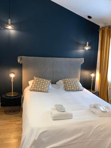 une chambre avec un grand lit blanc avec deux serviettes dessus dans l'établissement Petite Villa de impasse du Prieure, à Caen