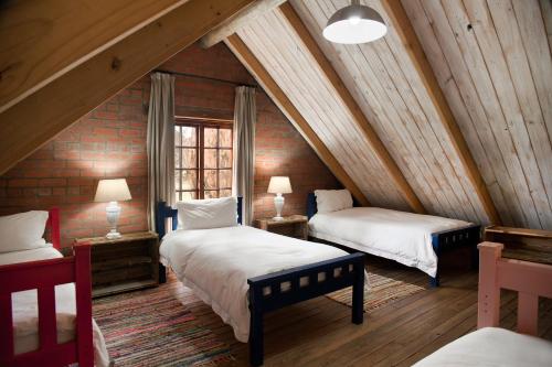 a attic room with two beds and a window at Dalmore Guest Farm in Bergville