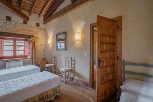 a bedroom with two beds and a wooden door at Capellan in Olmos de Ojeda