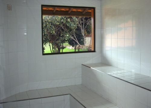 サン・トメー・ダス・レトラスにあるBosque dos Beija-Flores Pousada e Spaの窓のある白いタイル張りのシャワー