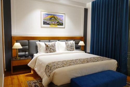 a bedroom with a large bed with blue curtains at WelcomHeritage Natraj, Mcleod Ganj in McLeod Ganj