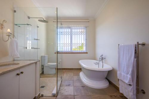 Un baño con ducha, lavabo e inodoro. en 22 Sewell Street, en Plettenberg Bay
