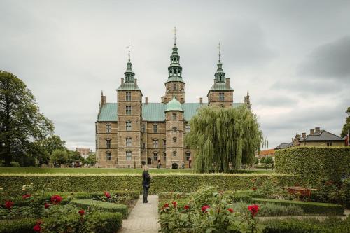 a woman walking in front of a castle with flowers at Beautiful Apartments on Strøget in Copenhagen City Center in Copenhagen