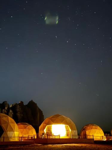 a group of domes lit up at night under the stars at Rum Angel Camp in Wadi Rum