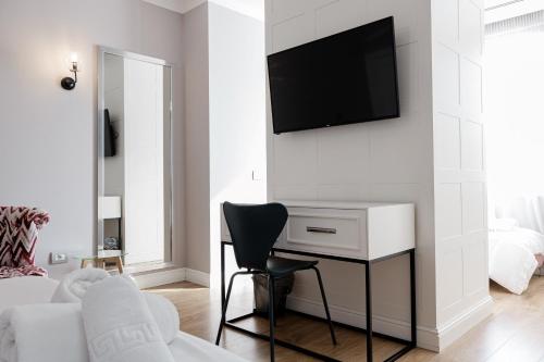a living room with a desk and a television on a wall at Boutique Hotel Whisky in Tirana