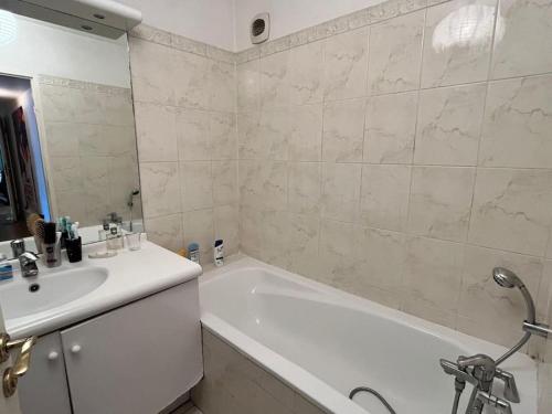 La salle de bains blanche est pourvue d'un lavabo, d'une baignoire et d'une baignoire. dans l'établissement 3 chambres terrasse et parking gratuit, à Paris