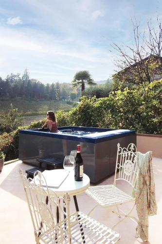 a woman sitting in a hot tub on a patio at ASILO in BAROLO in Barolo
