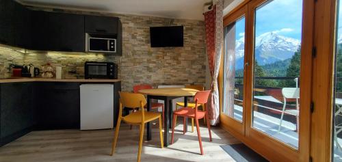 une cuisine avec une table et des chaises et une fenêtre dans l'établissement Appartement Saint Gervais les Bains piscine et vue imprenable Mont Blanc, à Saint-Gervais-les-Bains