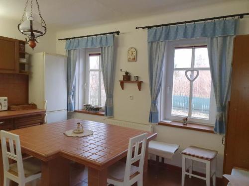 a dining room with a wooden table and two windows at Chalupa Potočná, Stará Ves, Jeseníky in Stará Ves