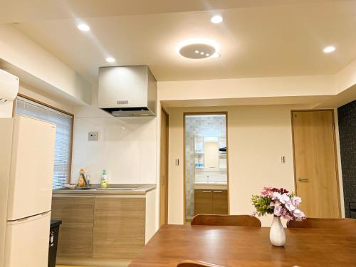 a kitchen with a table and a vase of flowers at RUKA guest house in Osaka