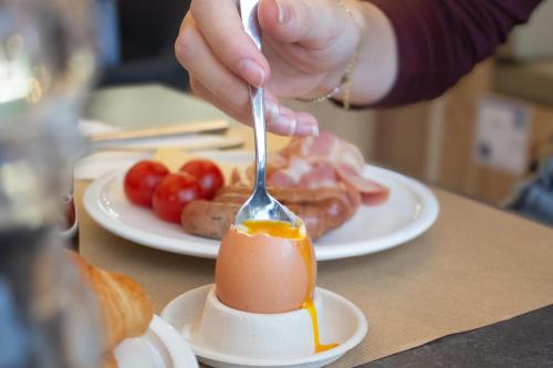 a person is eating an egg with a fork at Novotel Narbonne Sud A9/A61 in Narbonne