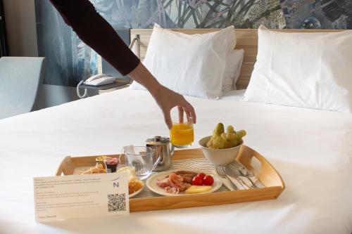 a tray of food on a bed with a plate of food at Novotel Narbonne Sud A9/A61 in Narbonne