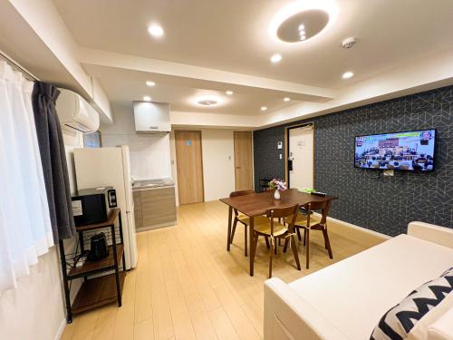 a living room with a dining room table and a kitchen at RUKA guest house in Osaka