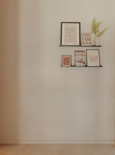 a white wall with three picture frames and a plant at CASA MARTINA Apartamentos de diseño en Pozuelo in Pozuelo de Alarcón