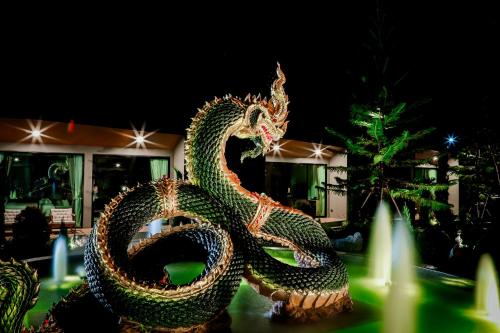 a statue of a dragon in front of a fountain at อนันตระปุระ รีสอร์ท บึงโขงหลง Anantara Pura Resort Bueng Khong Long in Ban Don Klang