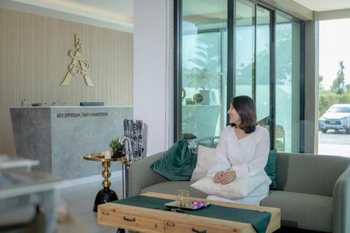 a woman in a robe sitting on a couch at อนันตระปุระ รีสอร์ท บึงโขงหลง Anantara Pura Resort Bueng Khong Long in Ban Don Klang