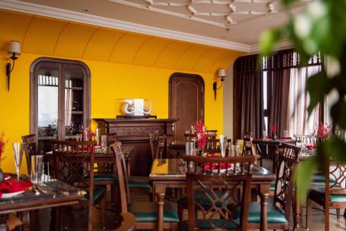 a restaurant with wooden tables and chairs and yellow walls at Hanoi Tirant Hotel in Hanoi