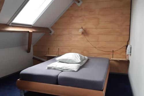 a bed in a room with a wooden wall at appartement met 5 slaapkamers in Moerstraten