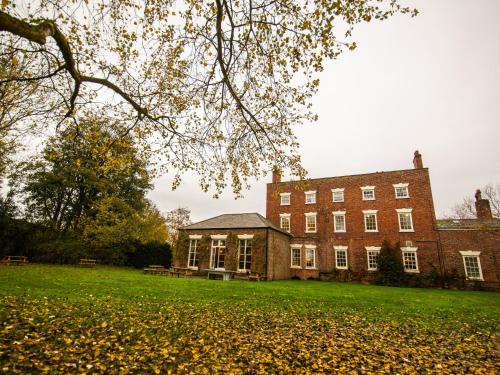 a large brick building with a grass field in front of it at YHA Chester Trafford Hall in Dunham on the Hill