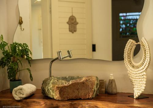 un bancone del bagno con lavandino, roccia e specchio di Pipa Sunset Home a Pipa