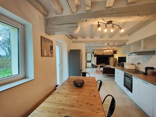 Il comprend une cuisine et une salle à manger avec une table en bois. dans l'établissement Charmante maison de campagne avec cheminée, à Souligné-Flacé