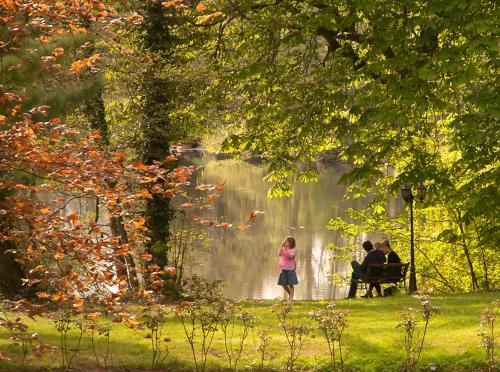 a group of people sitting on a bench near a pond at Belle Isle Sur Risle - Chateau Hotel & Spa in Pont-Audemer
