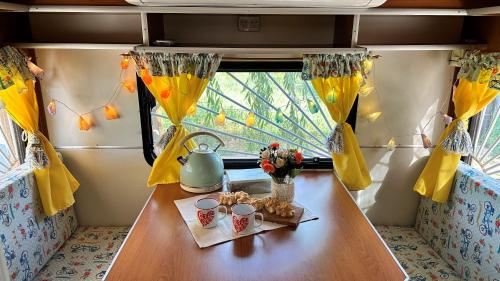 a table in a caravan with flowers and cups on it at Playa & Campo - Experiencia Glamping en Mar de Ajó in Mar de Ajó