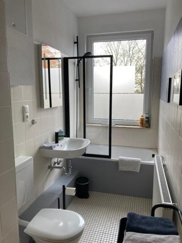 a bathroom with a sink and a toilet and a window at Direkt am Südstrand! in Wilhelmshaven