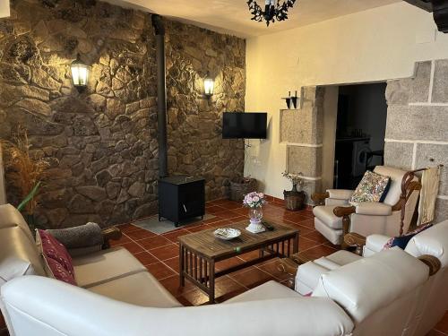 un salon avec des canapés et un mur en pierre dans l'établissement Ceclavinn Casa Rural, à Ceclavín