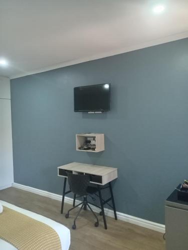 a room with a desk and a tv on a wall at Purple Steps Guest House in Kimberley